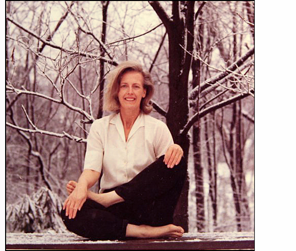 photograph of Jean Bayard at age 49, wearing blouse and slacks and sitting crosslegged outside on a table in the snow